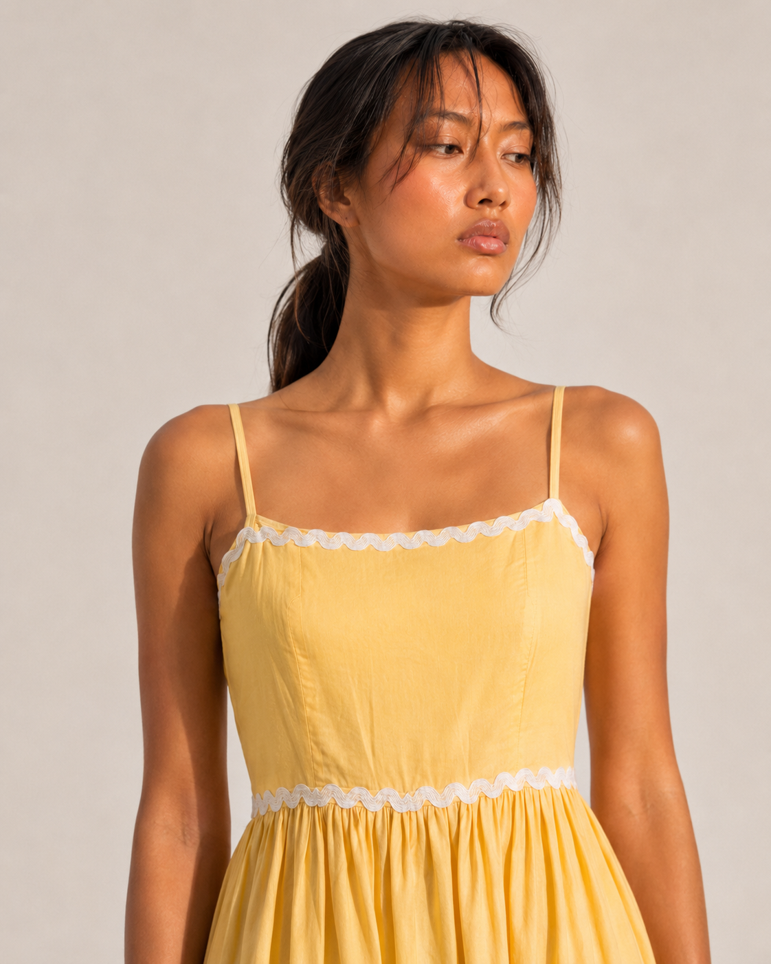 Detail of the white scalloped lace trim on JUNE's butter yellow tiered skirt.