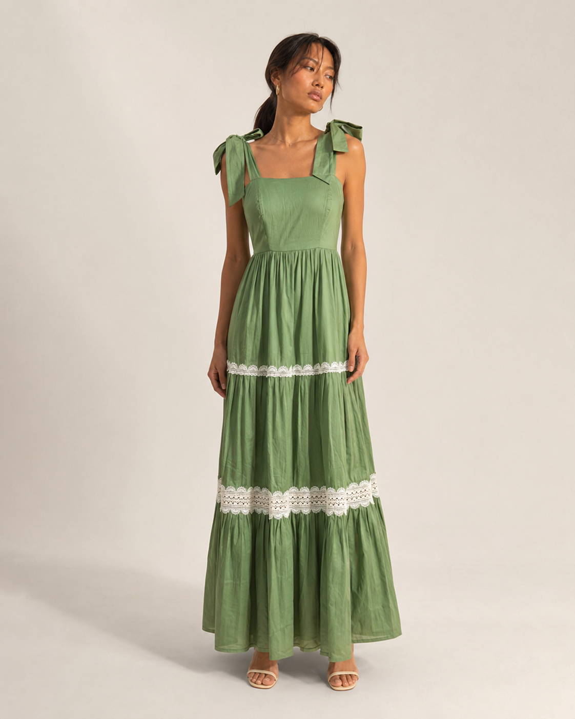 Model wearing MAEVE sage green tiered lace-trim maxi dress by Neha Sharma Label.