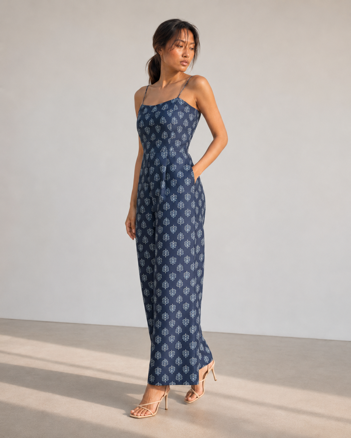 Three-quarter view of the IRIS navy wide-leg jumpsuit showing side-seam pockets.