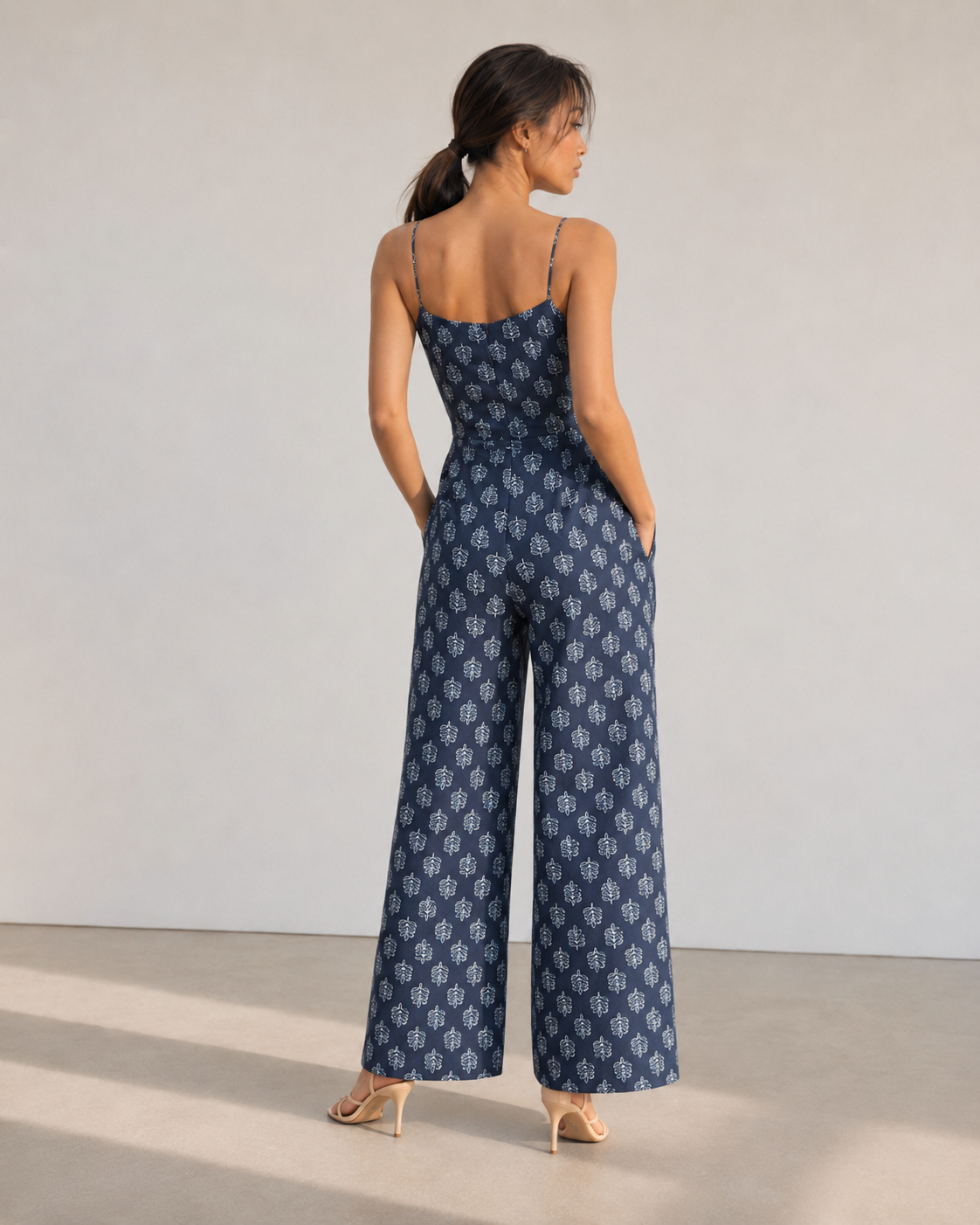Back view of the IRIS navy botanical print cotton jumpsuit with fitted bodice and wide leg.