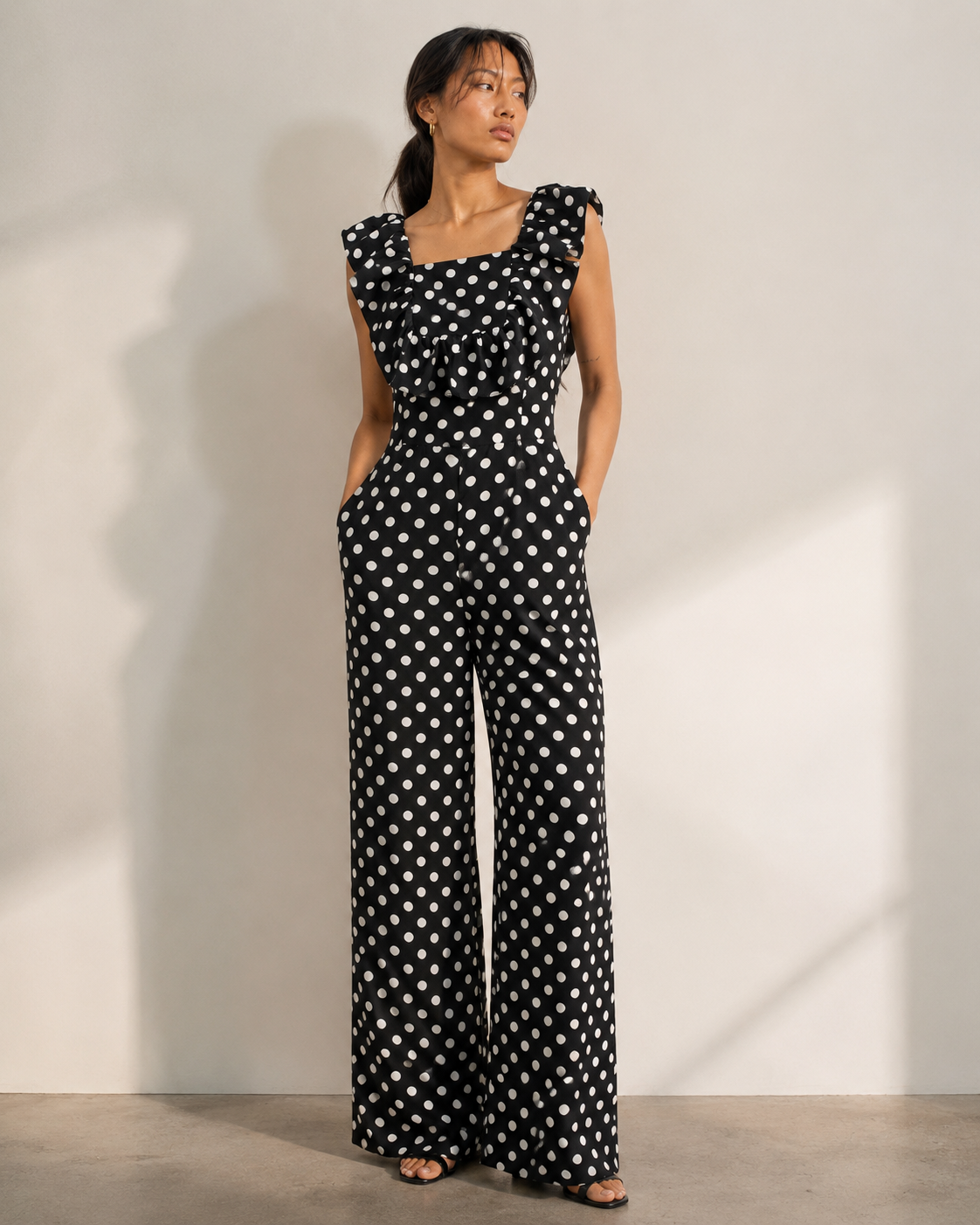 Model wearing ISLA black polka dot ruffle jumpsuit by Neha Sharma Label.