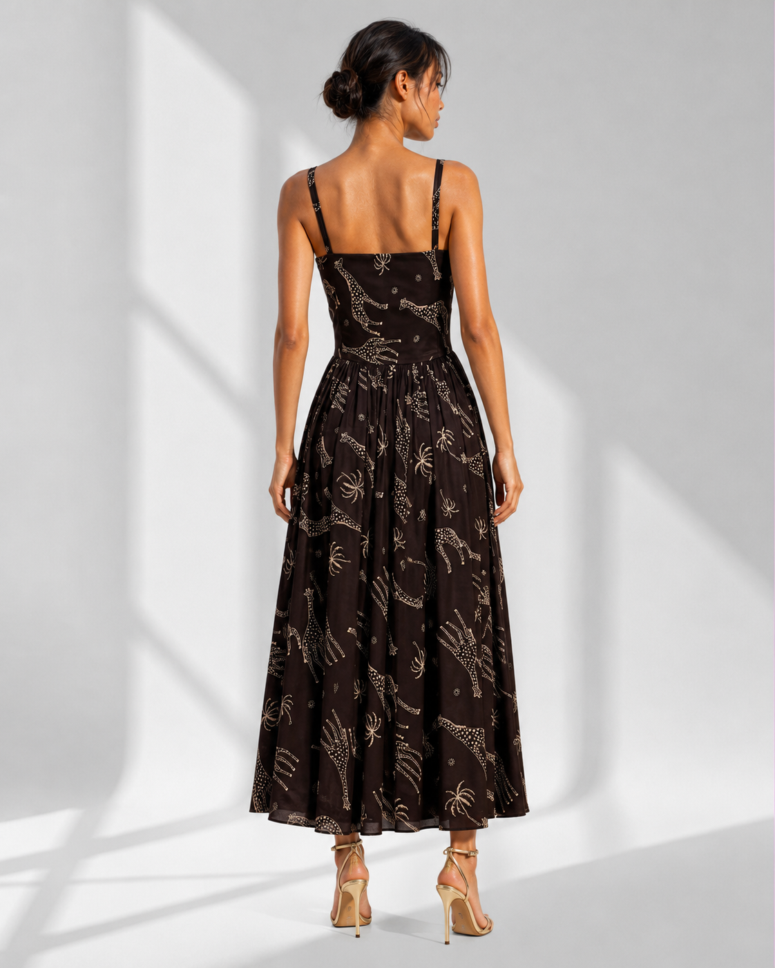 Back view of the NYALA black satin midi dress showing the panelled bodice and gathered skirt.