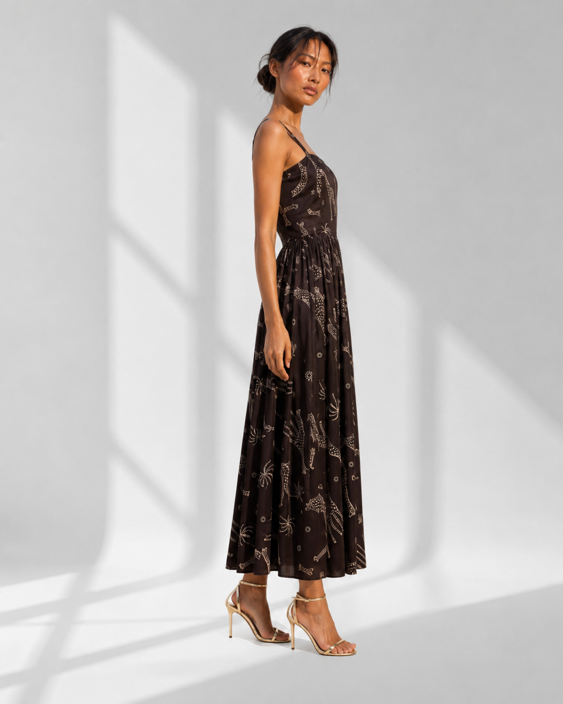 NYALA black safari print midi dress in profile, slim straps and a full ankle-grazing satin skirt.